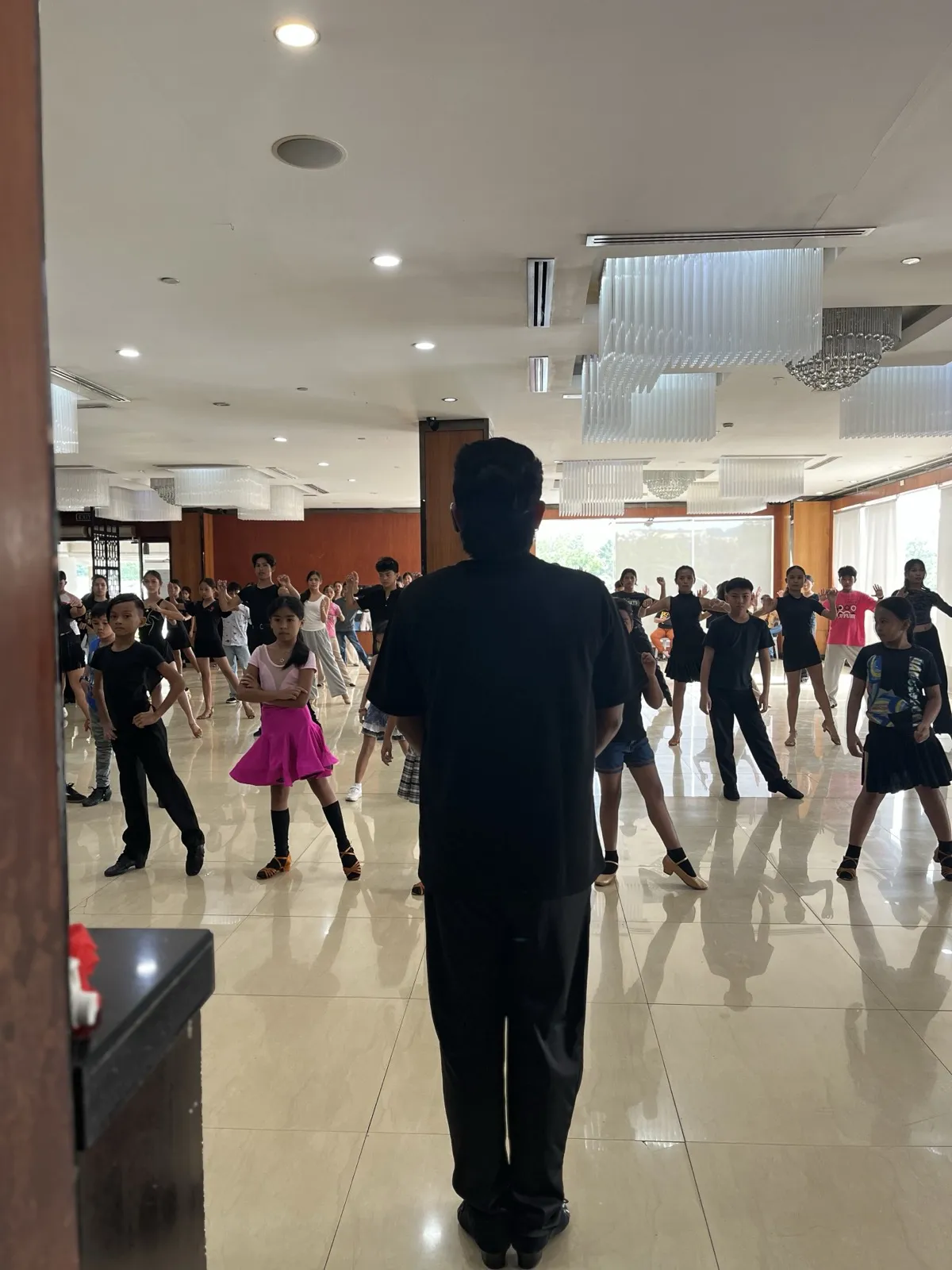 Instructor leading large DanceSport class of children
