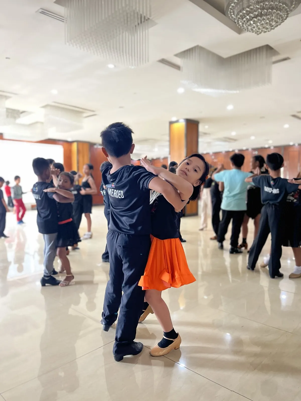 Two young children dancing together in ballroom hold
